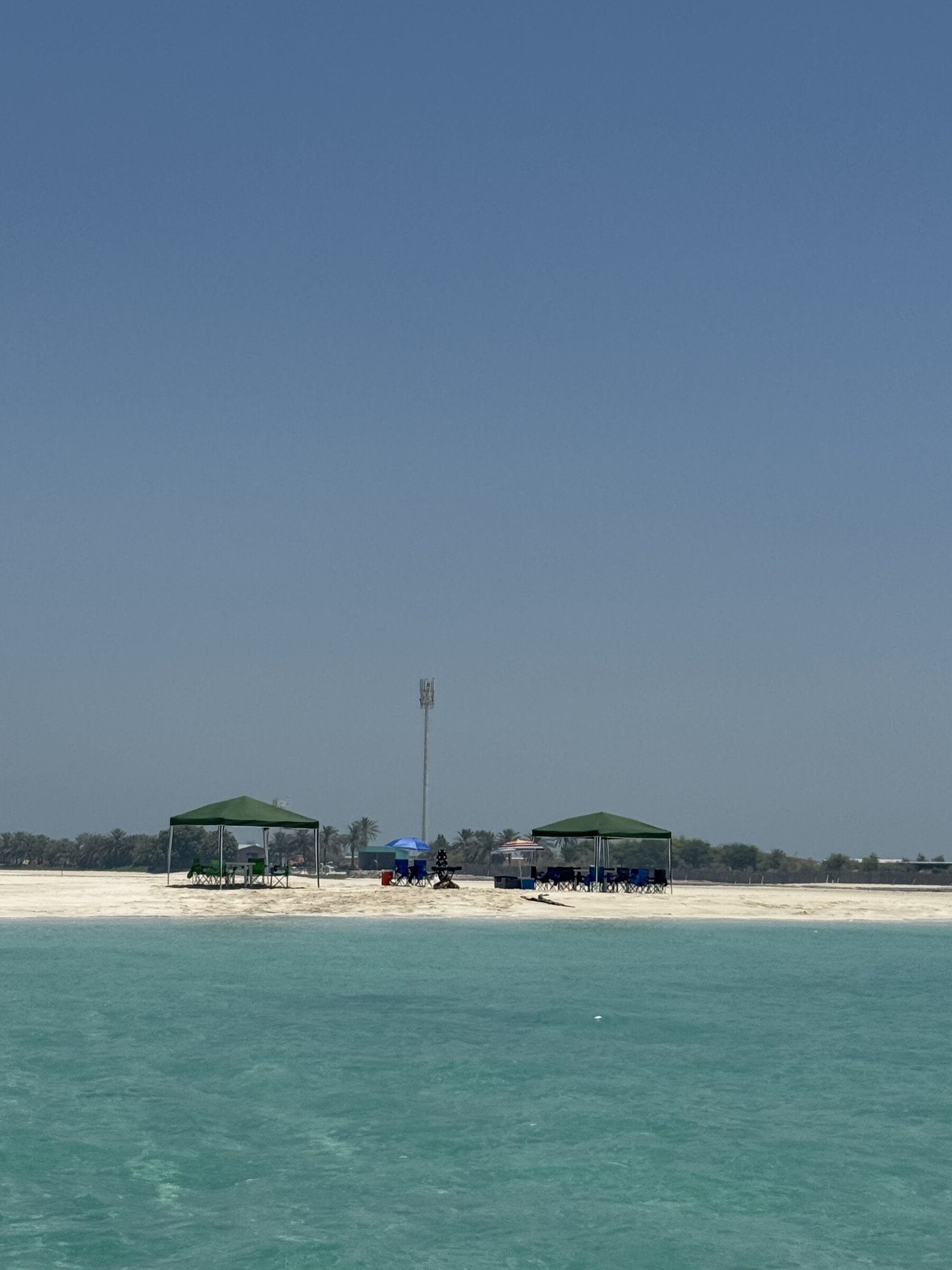 Shaded camp with rugs and cushions set up on a private island sandbank near Abu Dhabi